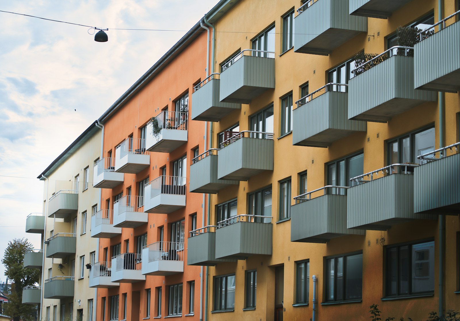 Putsade flerbostadshus i gult och orange med rader av balkonger längs en gata