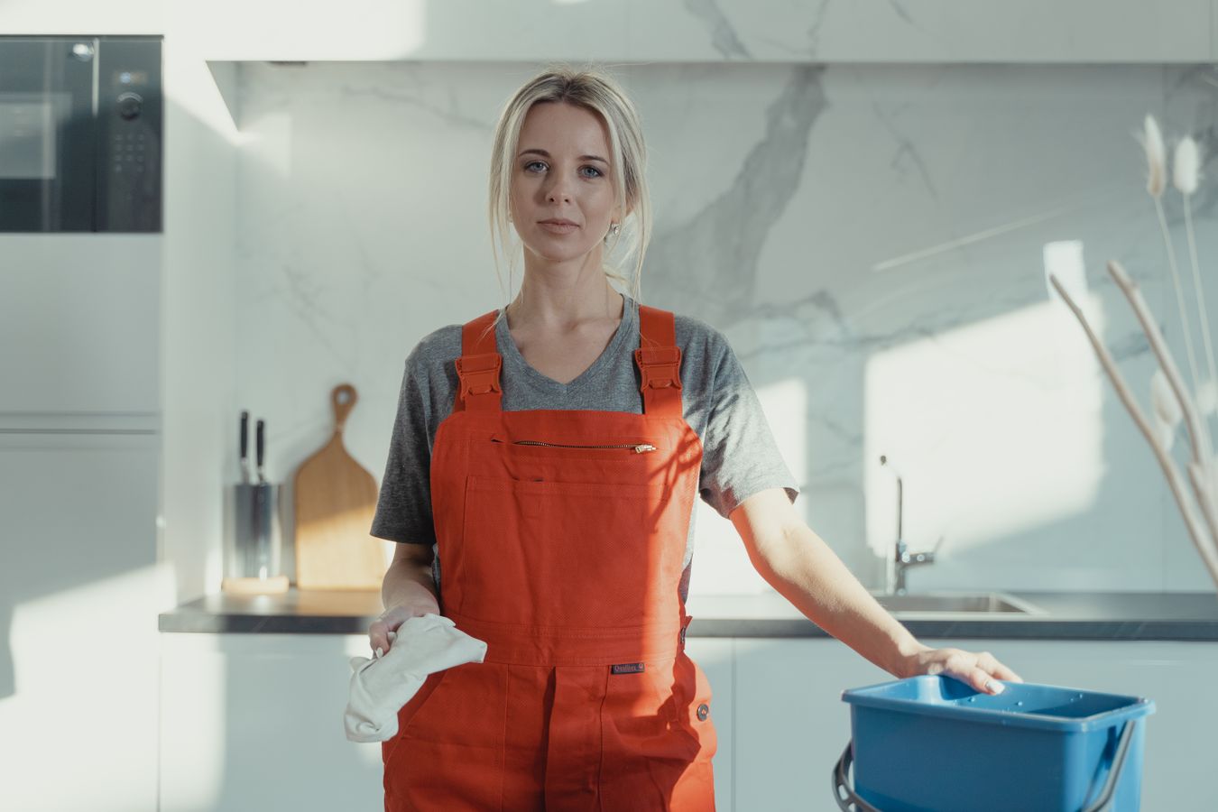 Person i arbetsoverall med hink och trasa städar ett kök