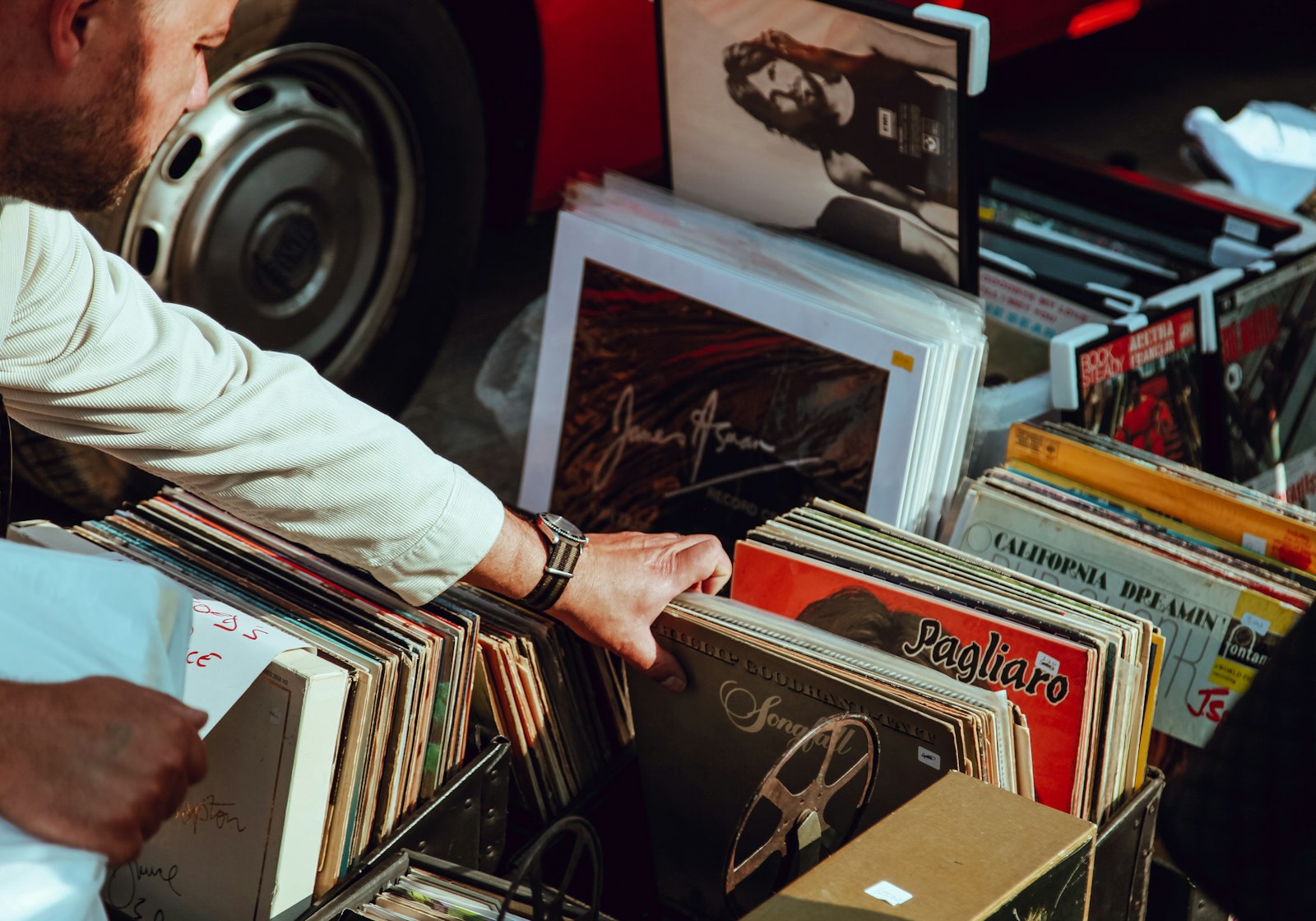 Hand som bläddrar genom lådor med begagnade vinylskivor