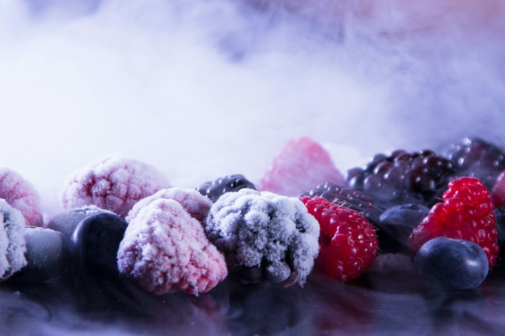 Frysta hallon, björnbär och blåbär täckta av frost