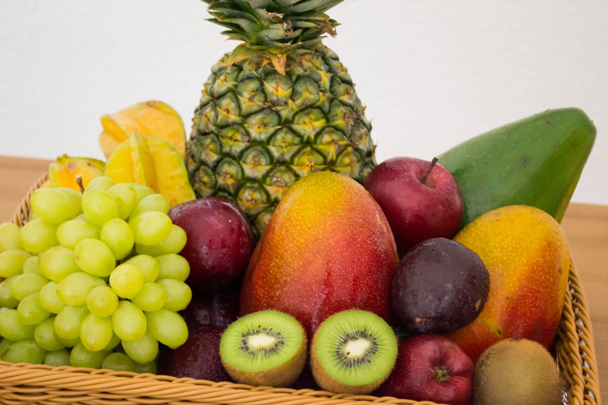Färgglad fruktkorg med ananas, vindruvor, mango och kiwi