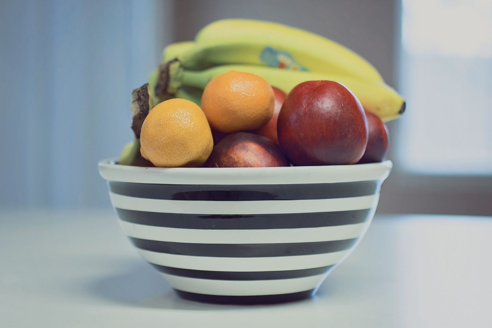 Randig skål med bananer, apelsiner och äpple