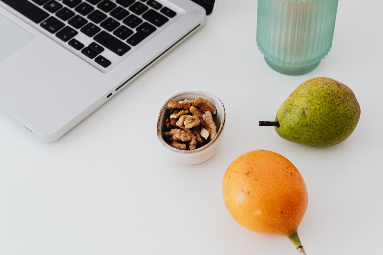 Laptop med päron och frukt på ett skrivbord