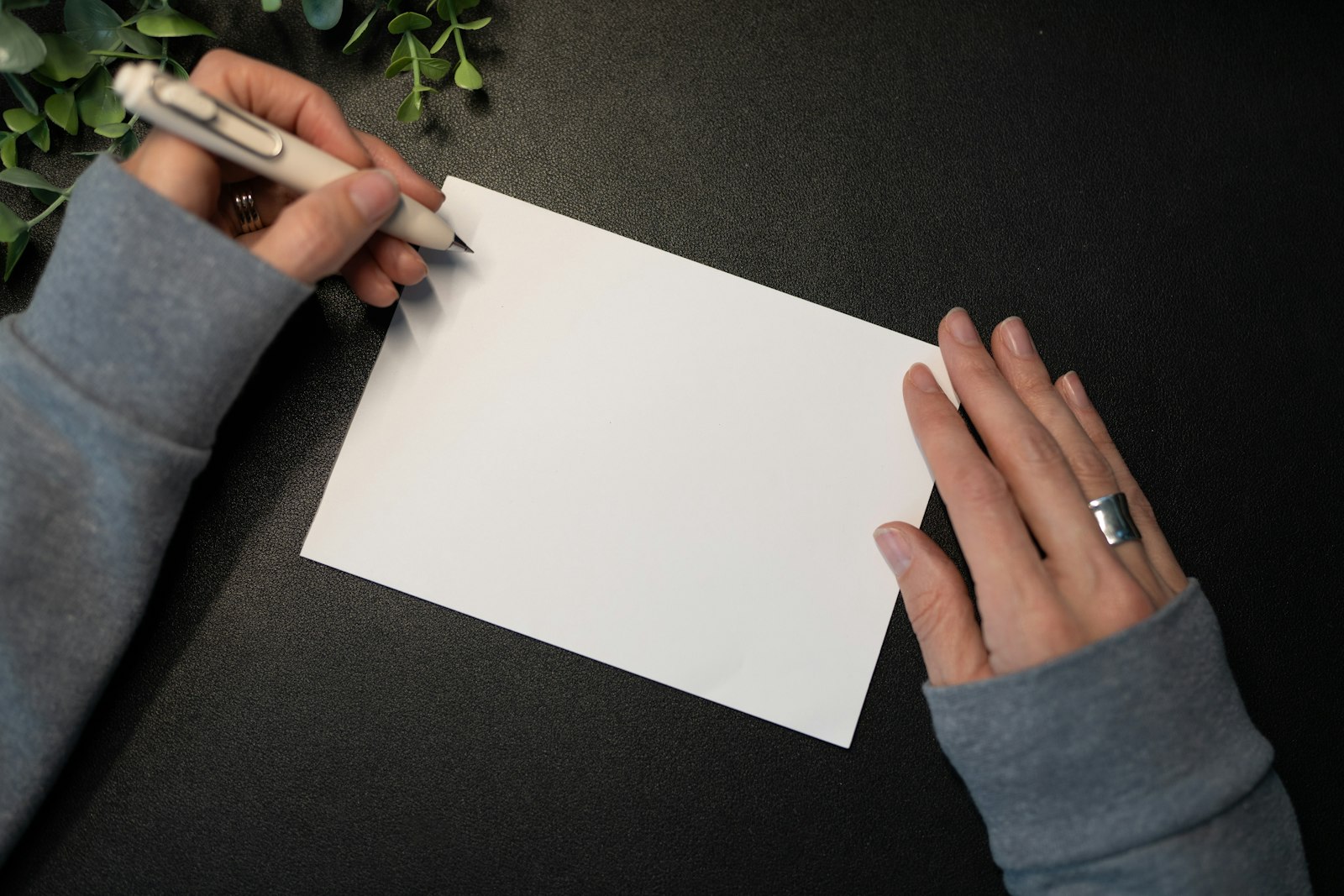 A person writing a letter by hand at a desk