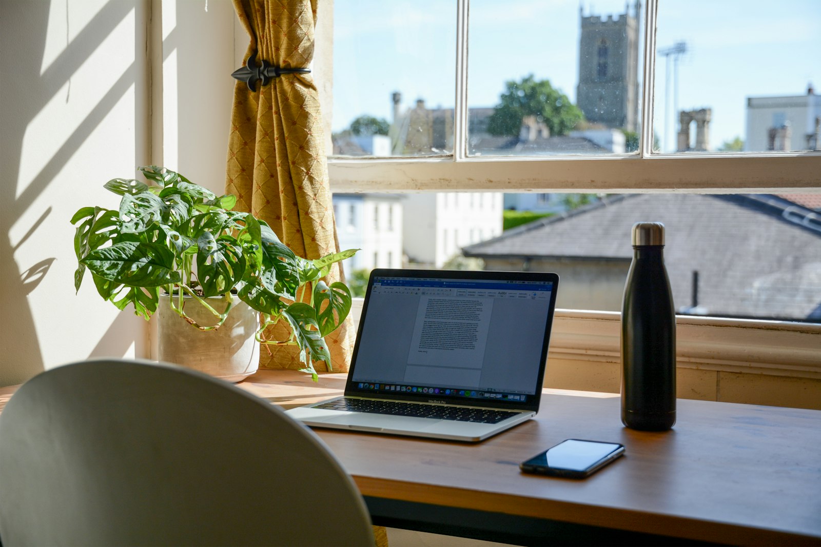 A home office desk with a laptop by a window