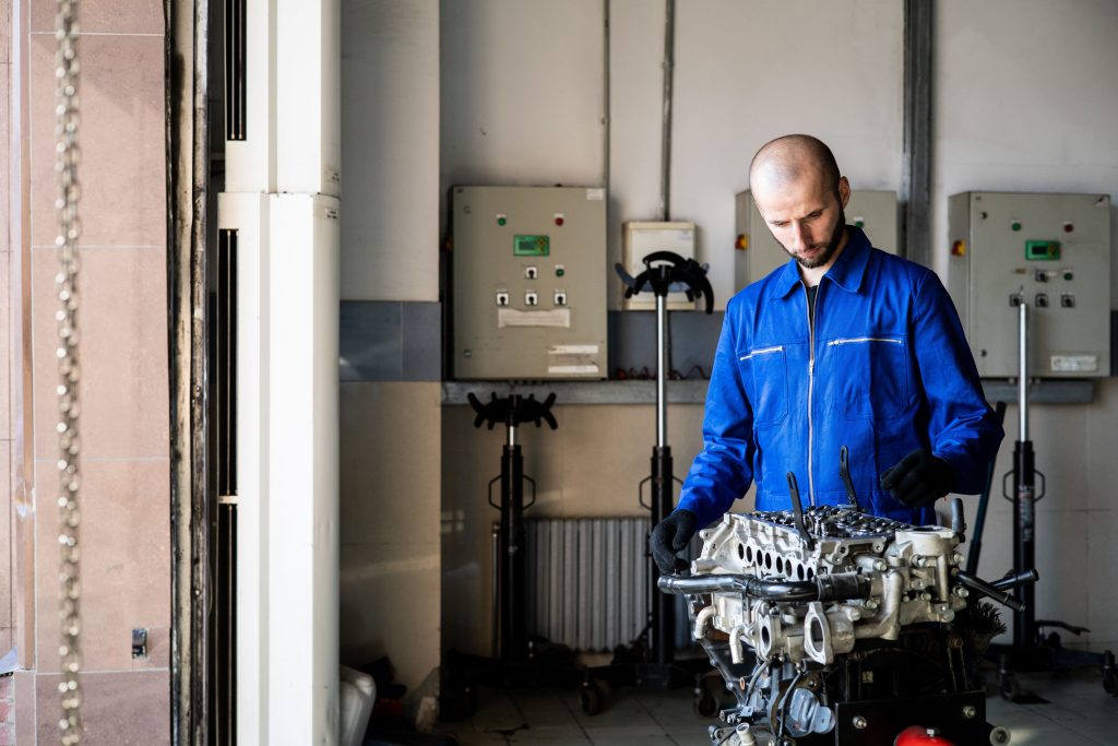 Mekaniker arbetar med en isärtagen motor på en ställning i en verkstad