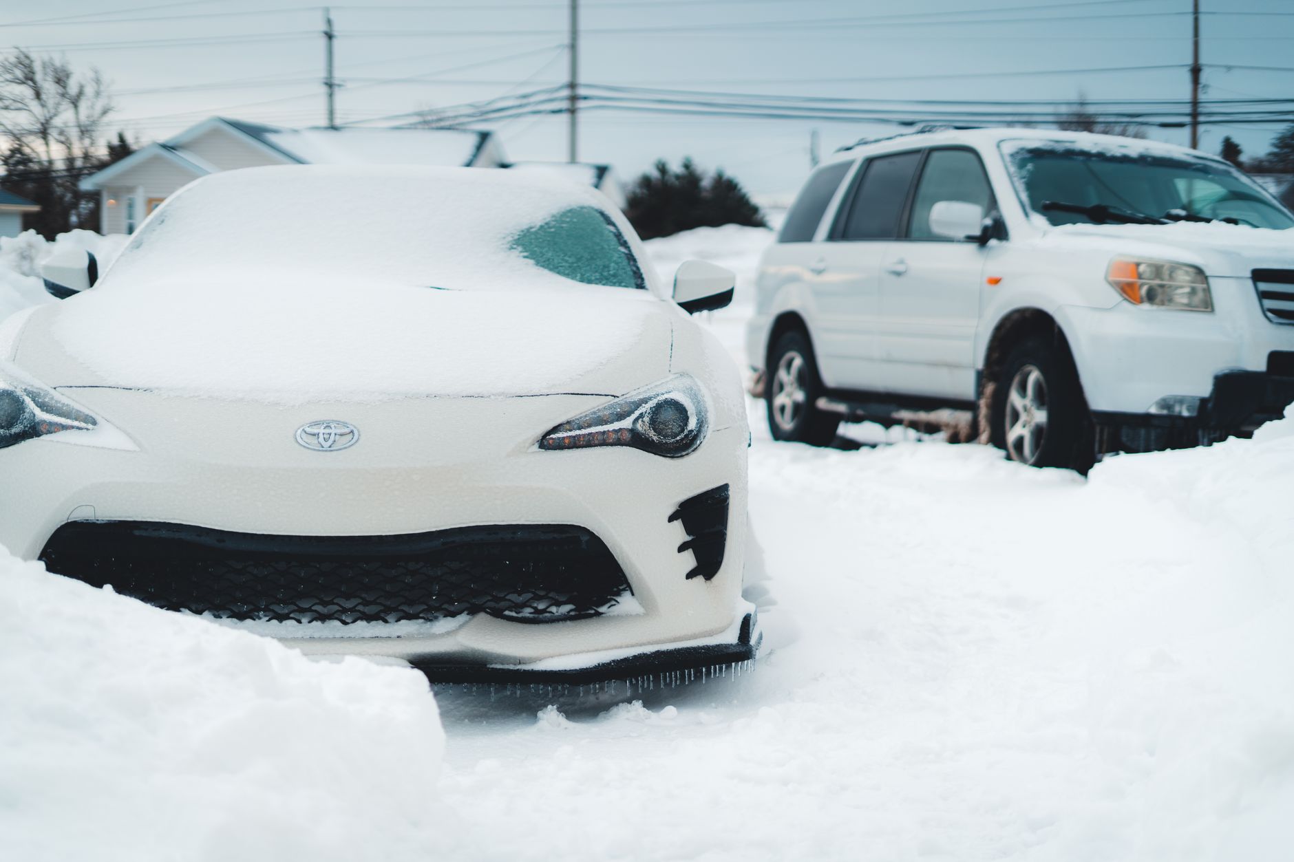 Två snötäckta bilar parkerade på en uppfart en kall vintermorgon