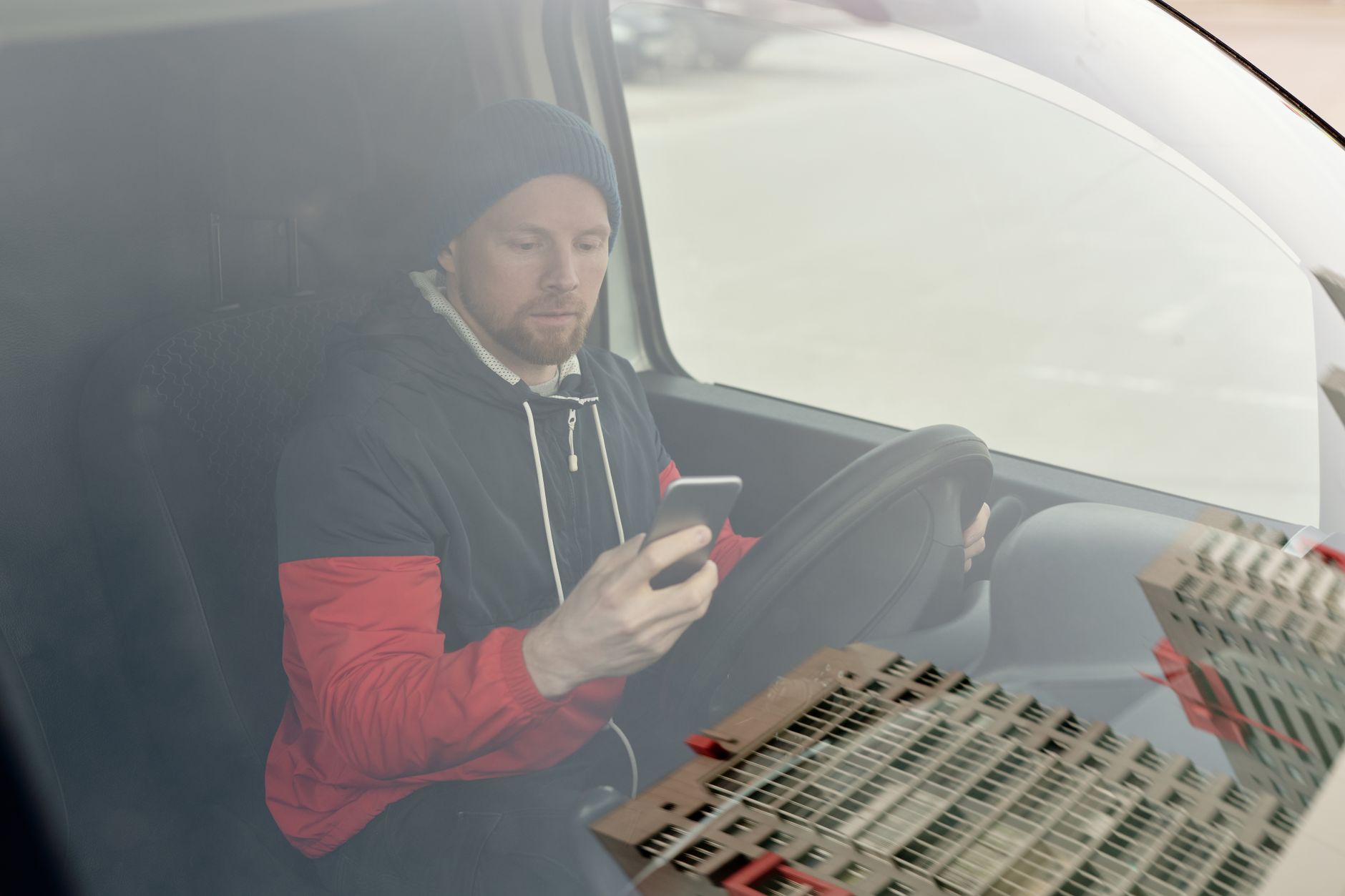 Hantverkare sitter i sin bil och läser ett meddelande i mobilen