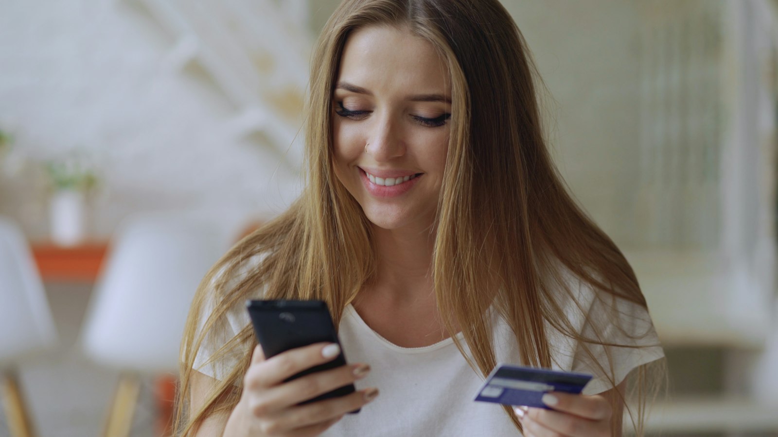 Kvinna med mobiltelefon och betalkort i händerna