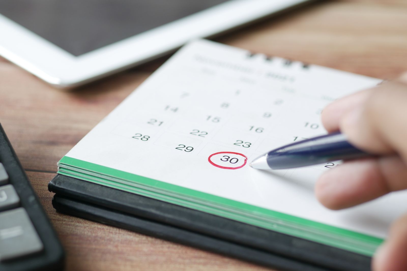 Hand som med penna ringar in ett datum i en bordskalender
