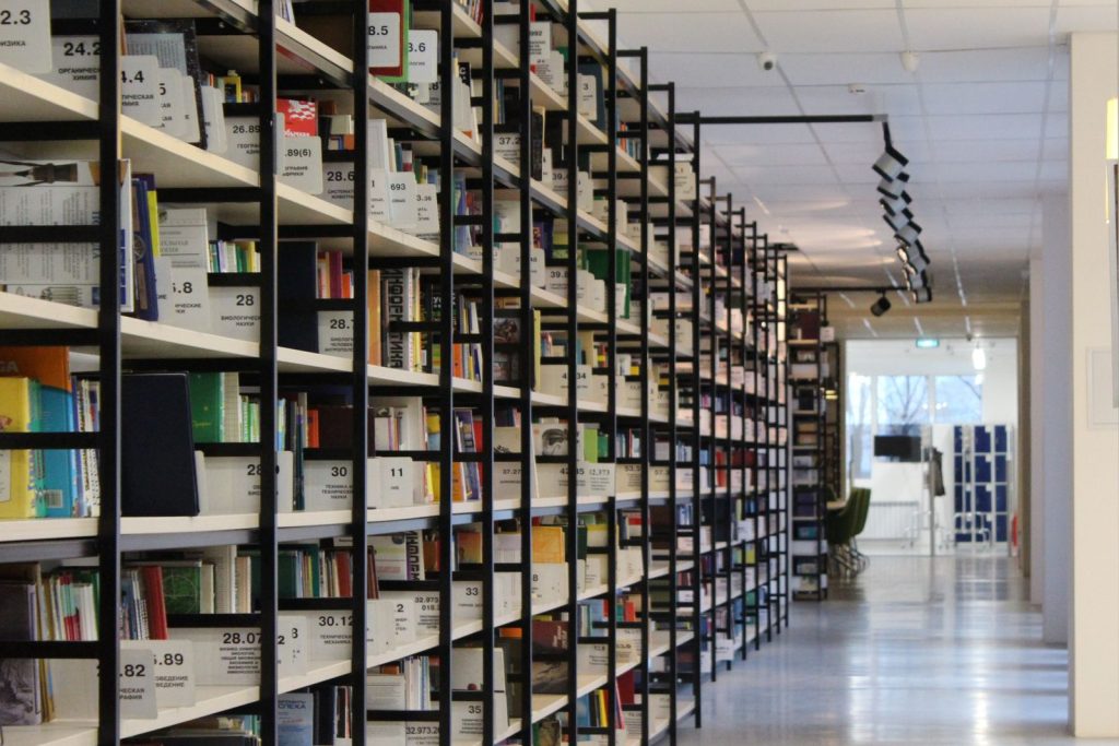 Ljust bibliotek med långa rader av bokhyllor fyllda med böcker