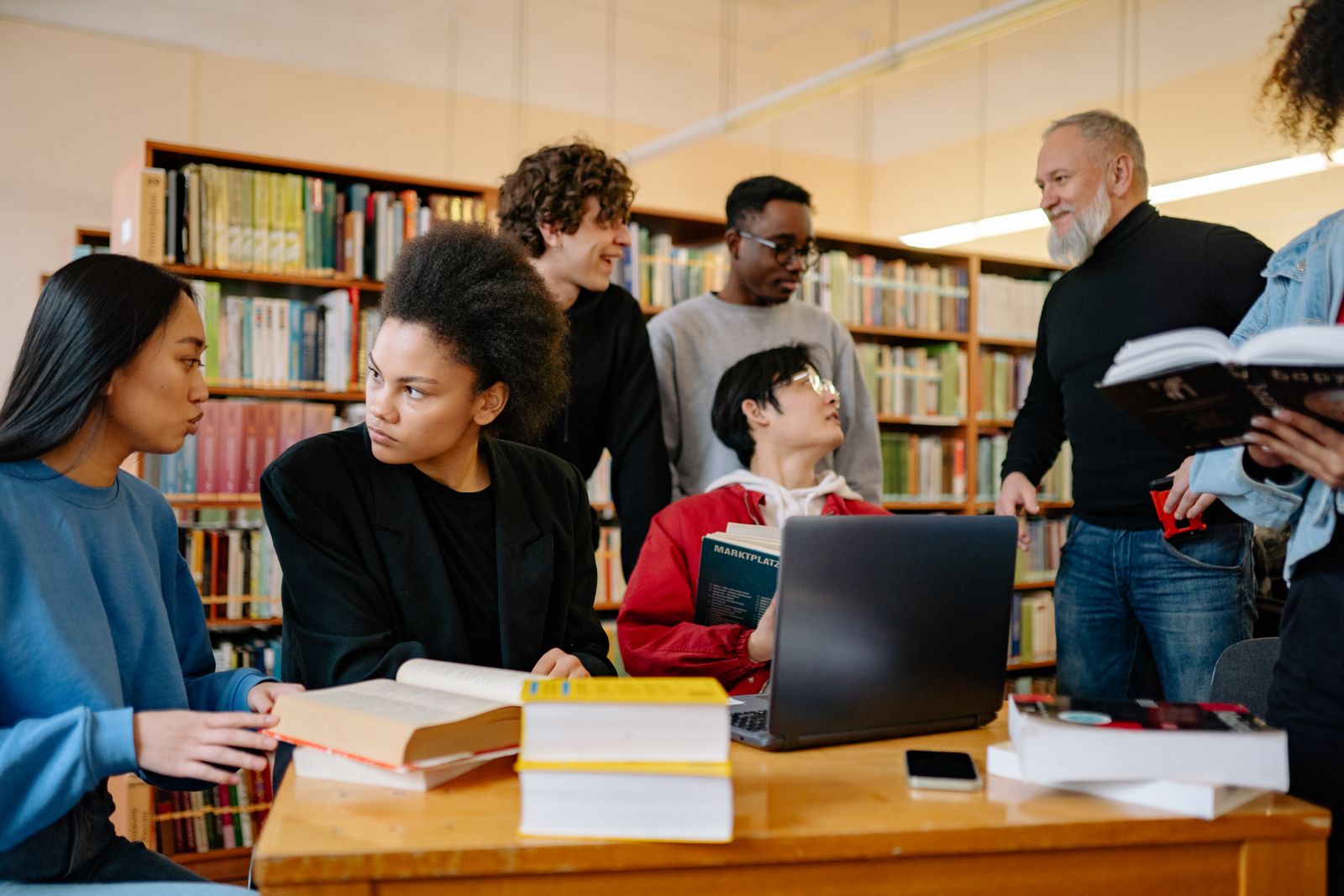 Studenter studerar tillsammans med böcker och laptop i ett universitetsbibliotek