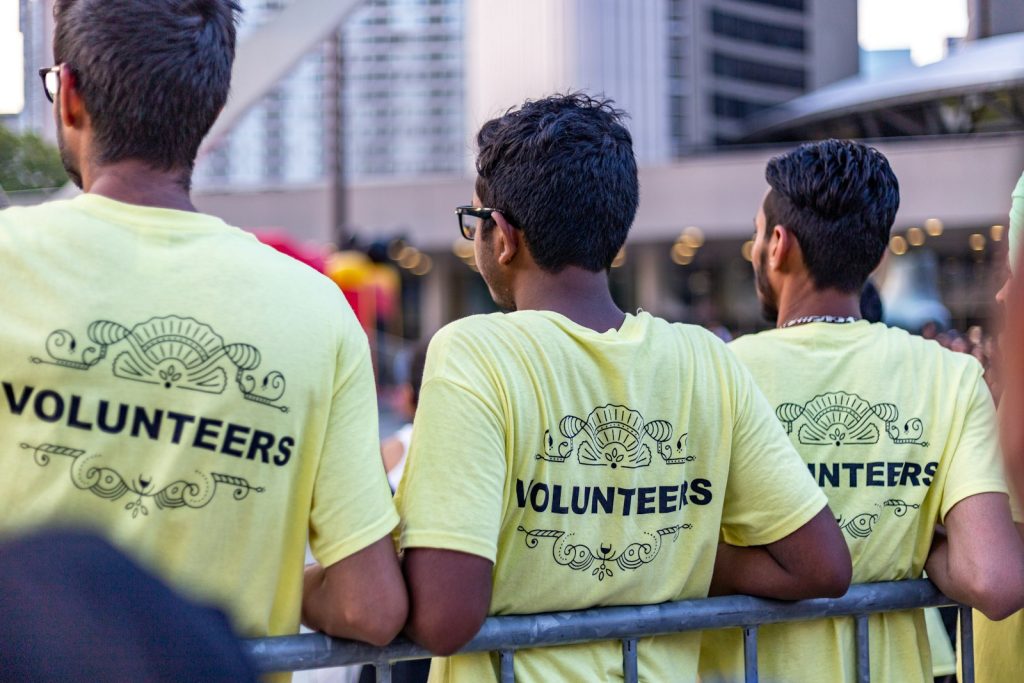 Tre volontarer i gula t-shirts med texten Volunteers vid ett samhallsprojekt