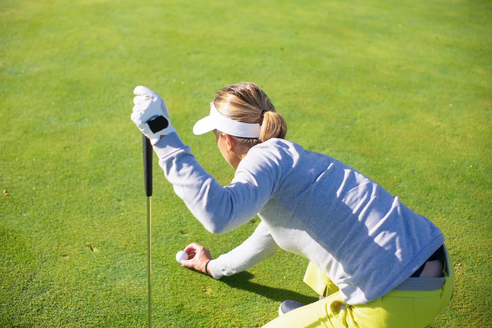 Golfare som koncentrerat läser greenen inför en putt en solig dag