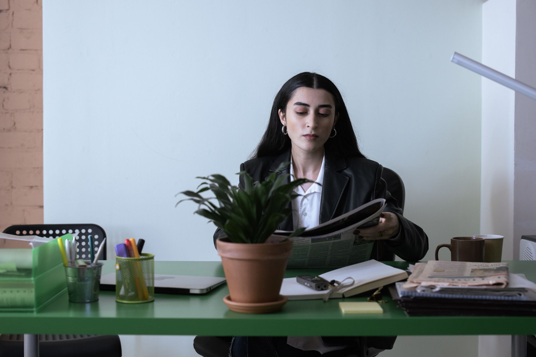Kvinna läser en tidning vid ett skrivbord på ett kontor