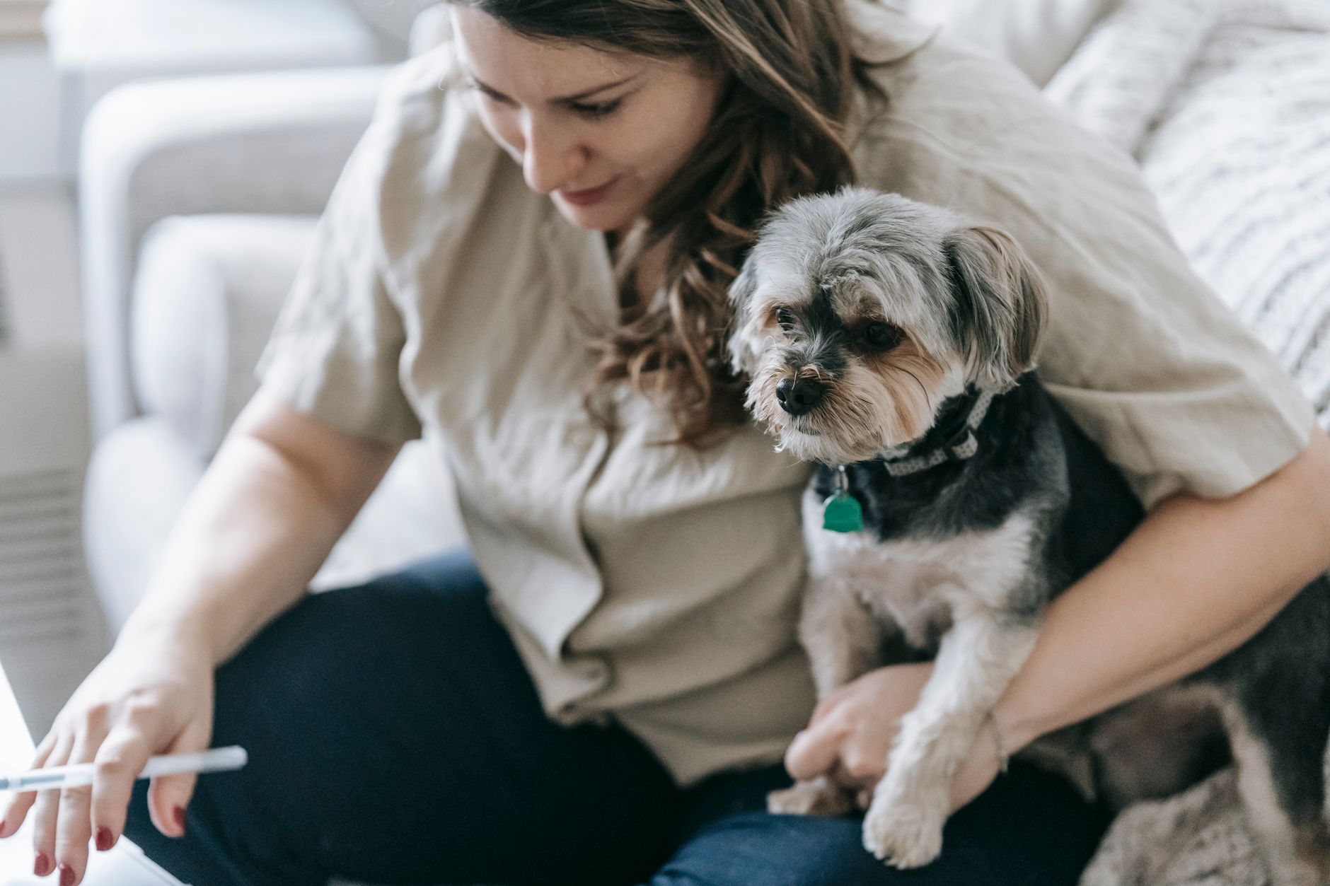 Hundägare med penna och en liten hund i famnen