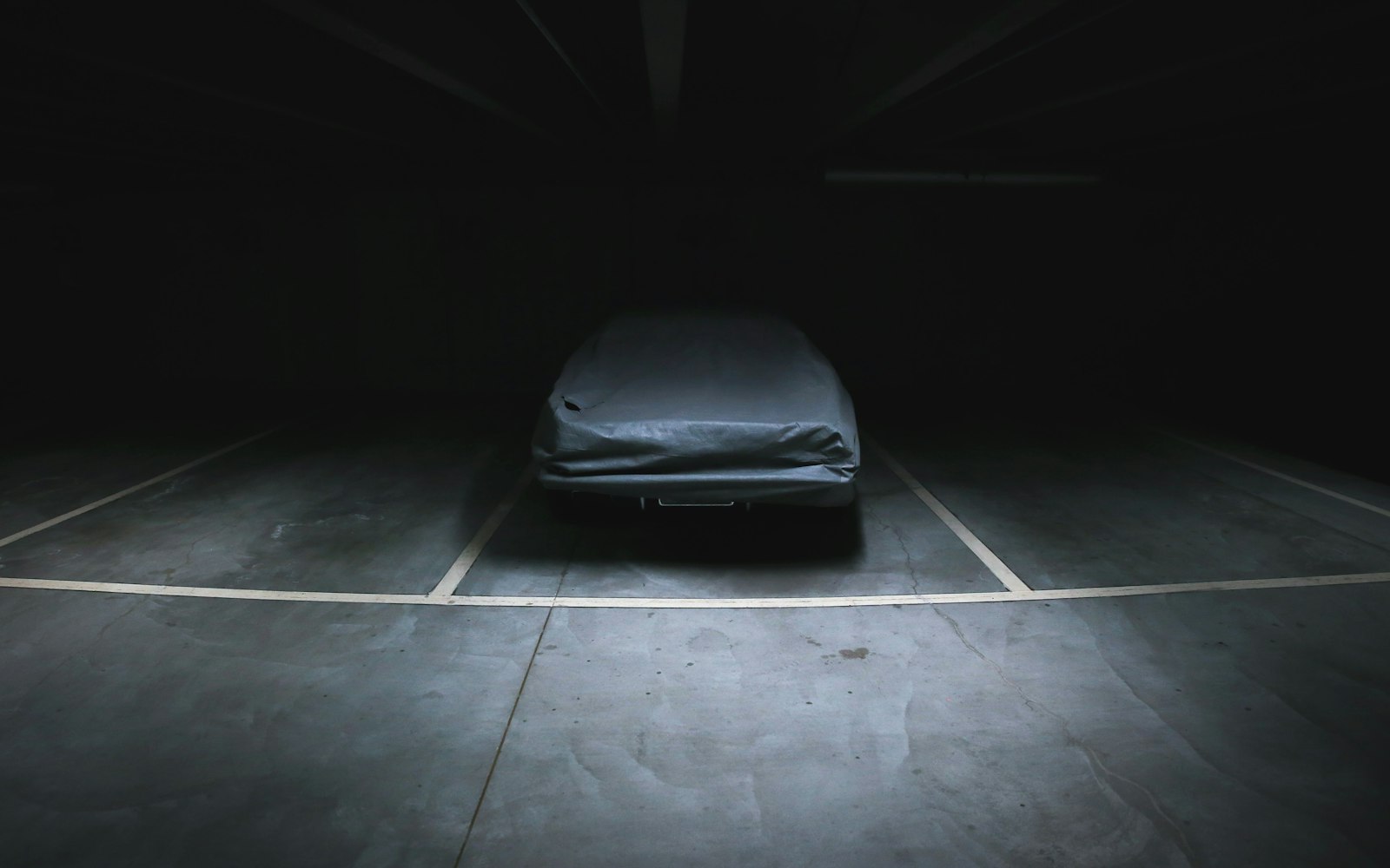 Överdragen bil som står parkerad i ett mörkt garage