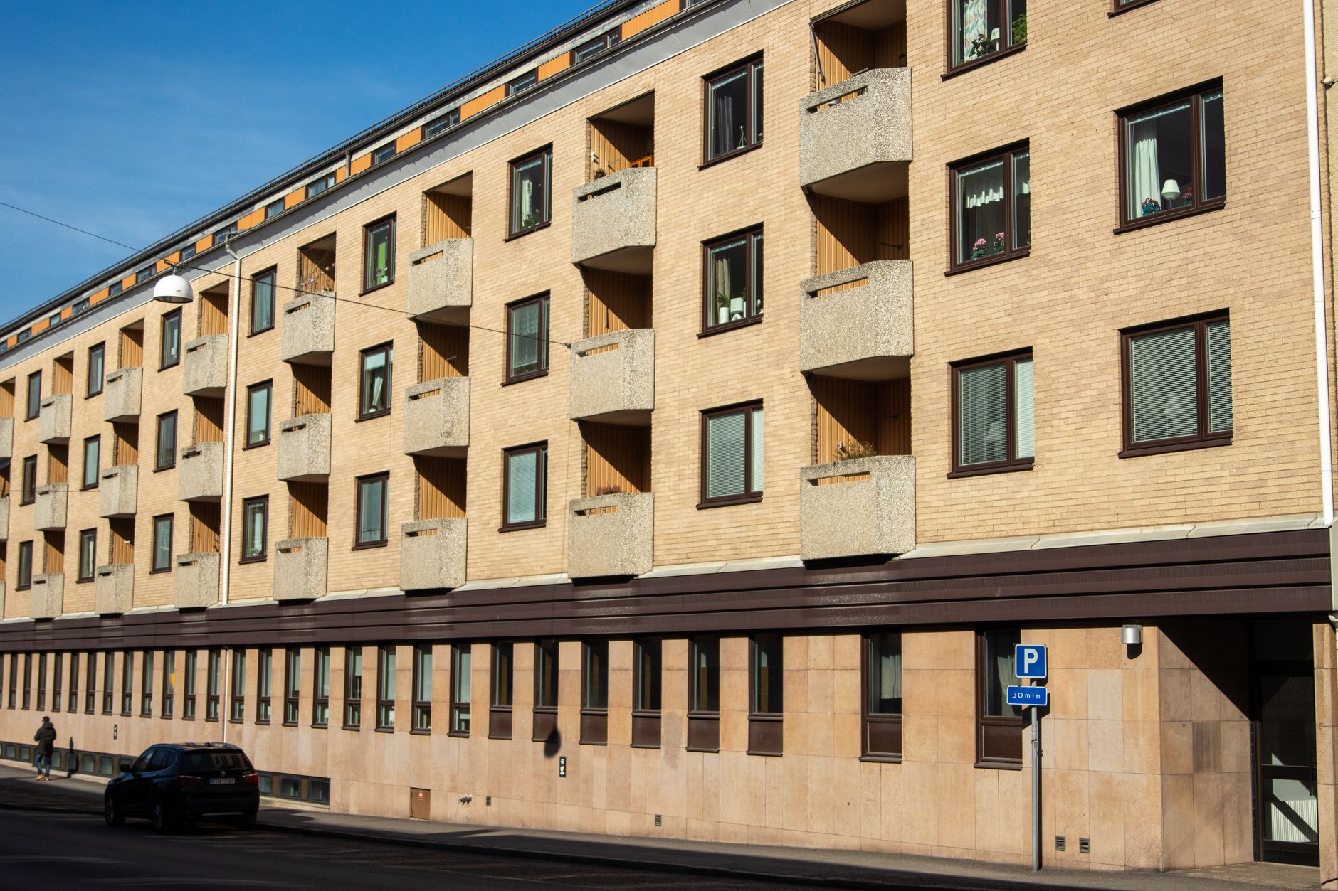 Tegelfasad på svenskt flerbostadshus med balkonger en solig dag