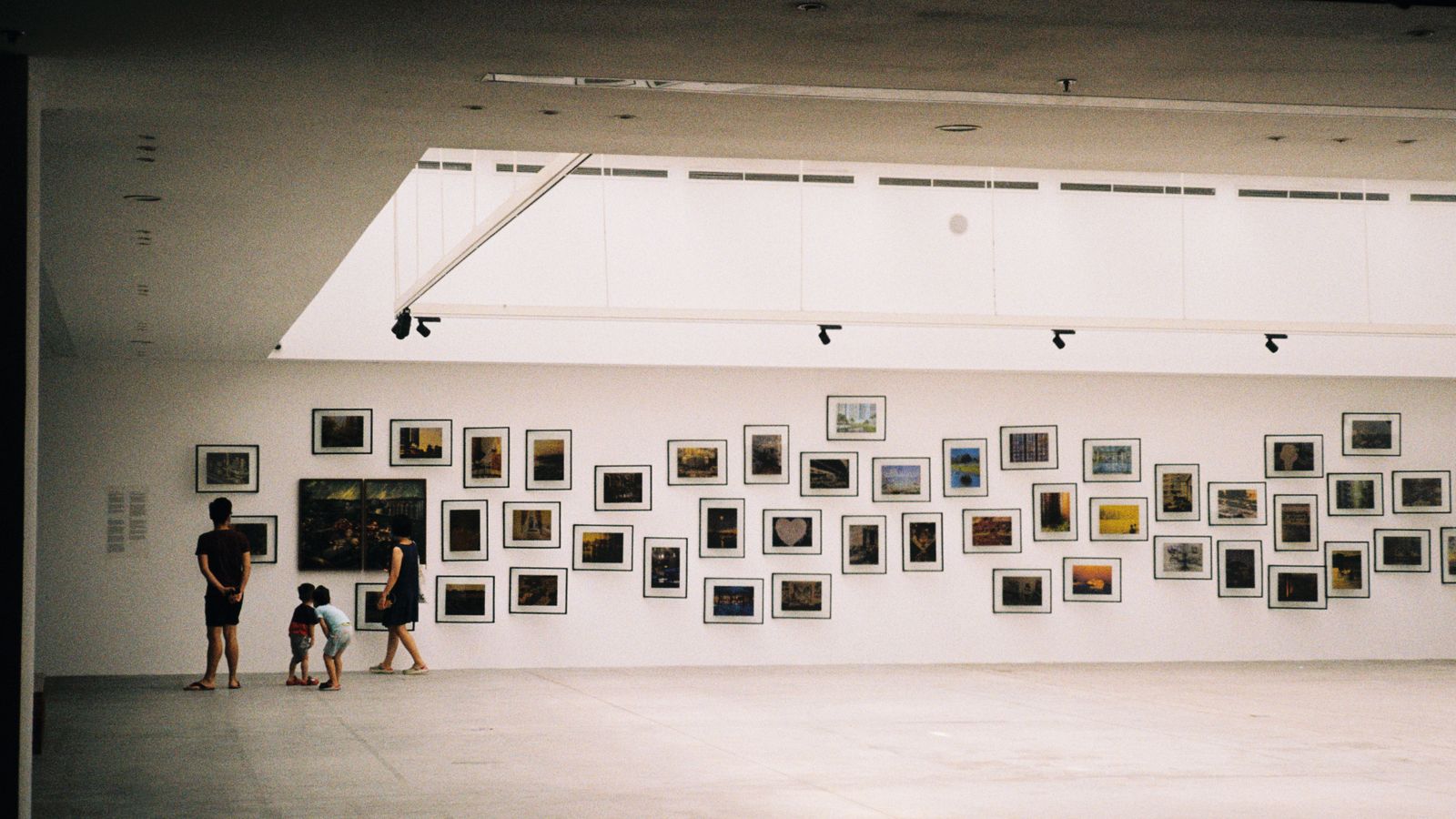 En familj med barn som utforskar en fotoutställning i en ljus museihall
