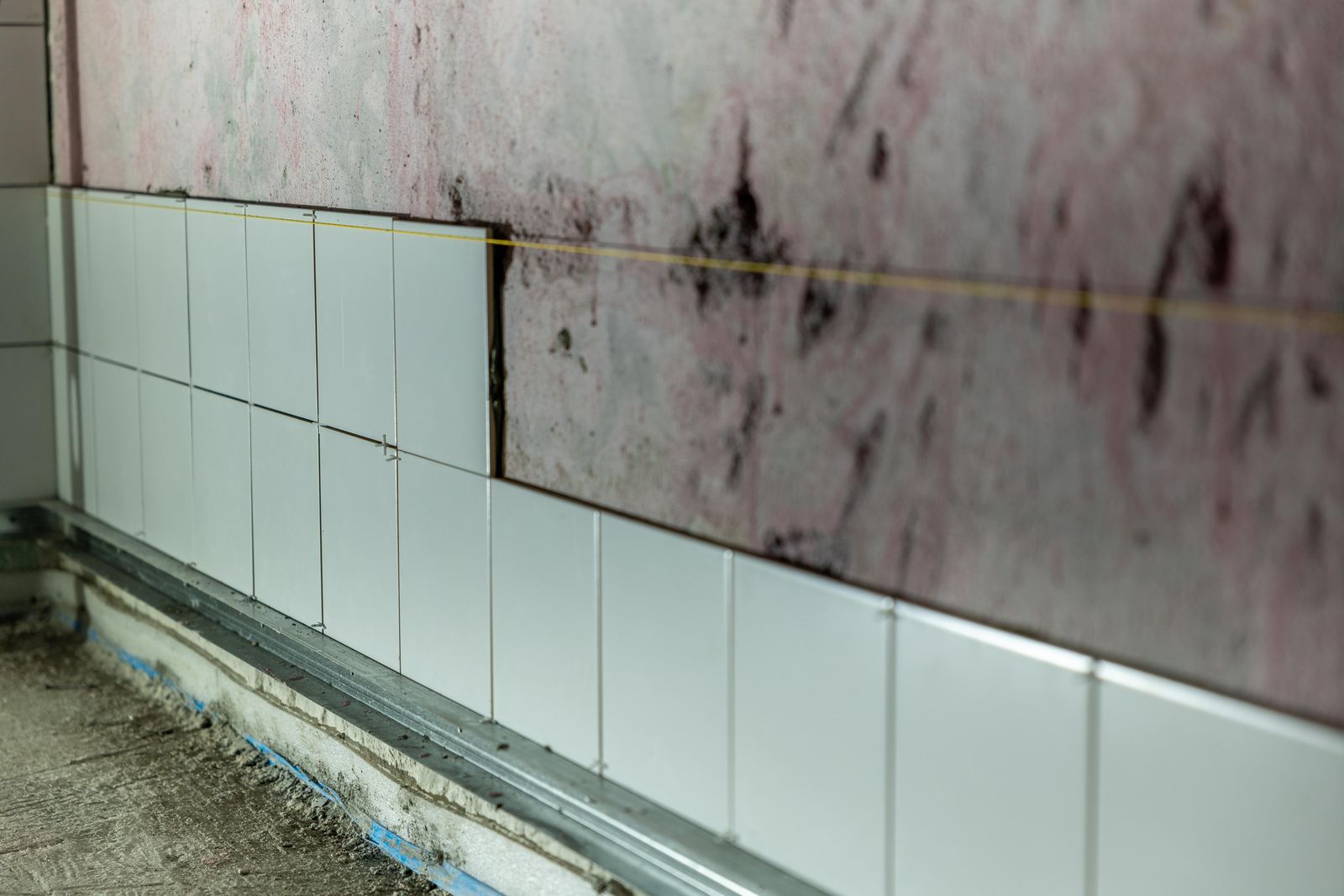 Badrum under renovering med kakelsättning över tätskikt på våtrumsvägg