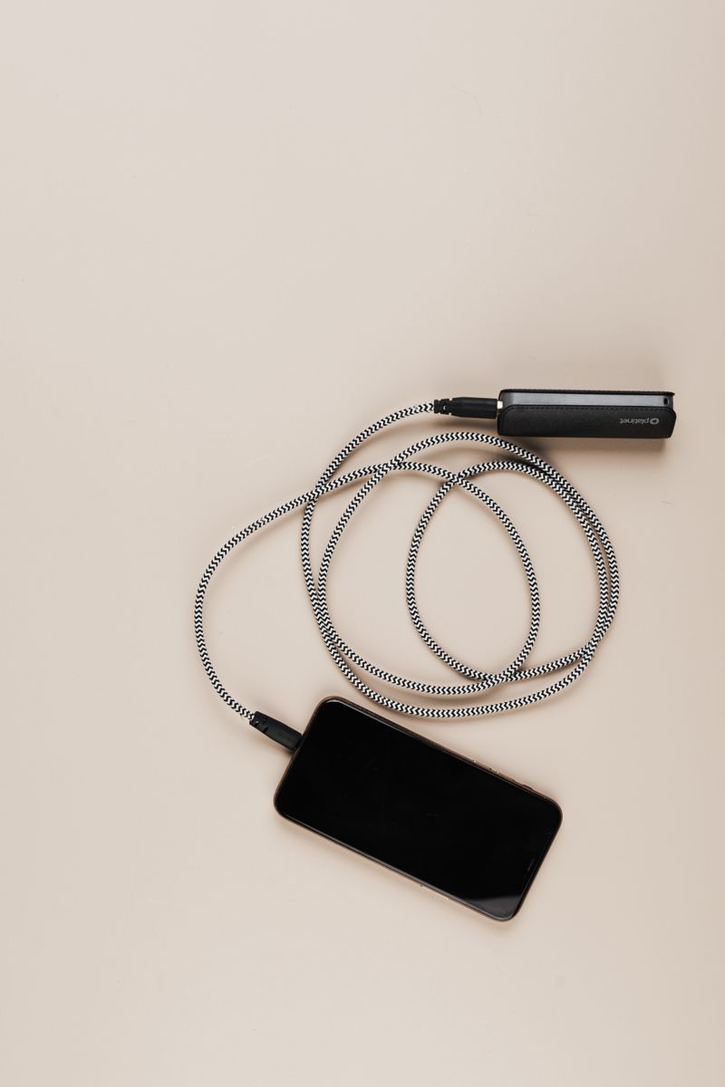 Mobiltelefon som laddas med kabel och powerbank på ett bord