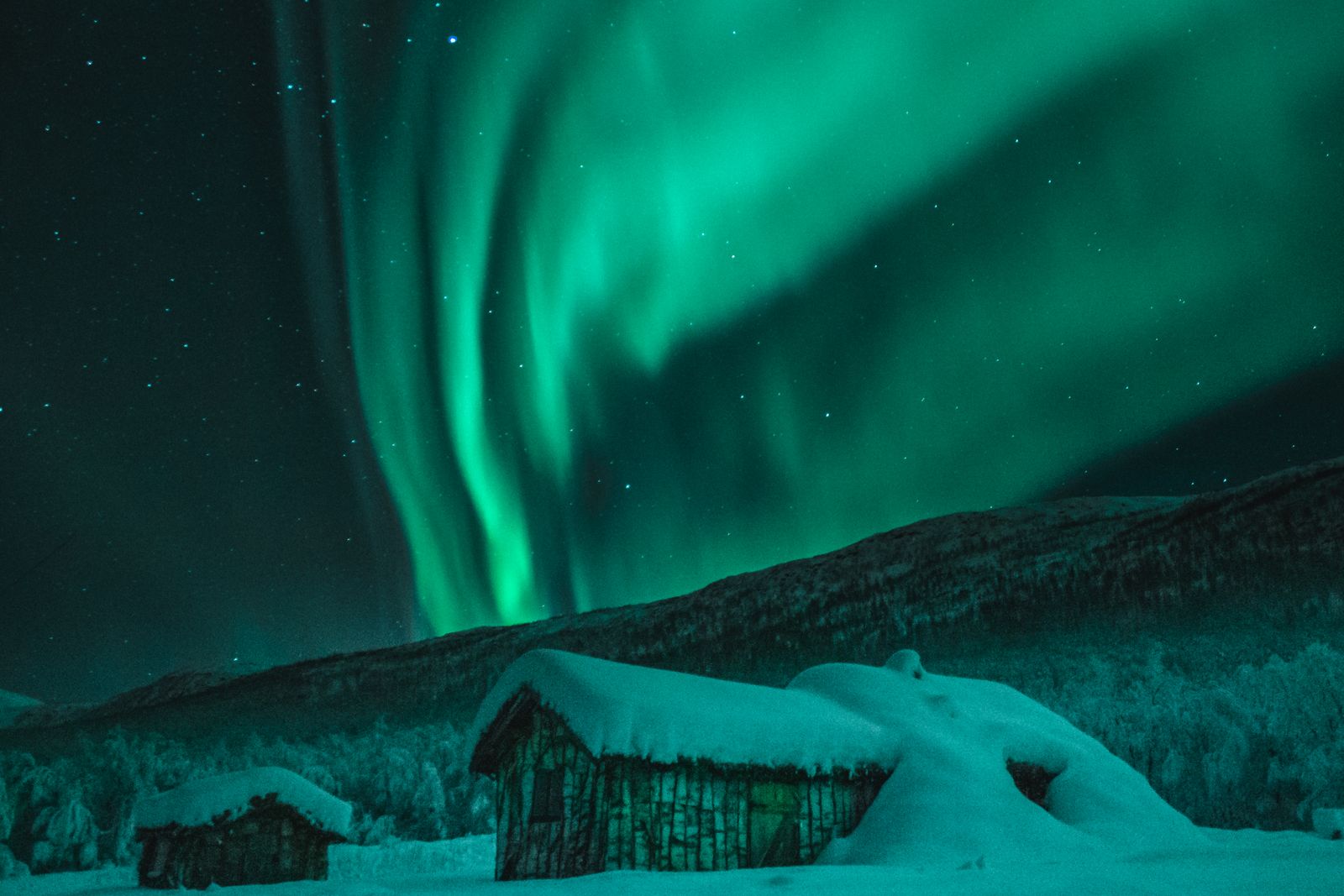 Northern lights over a snowy cabin in Arctic Sweden