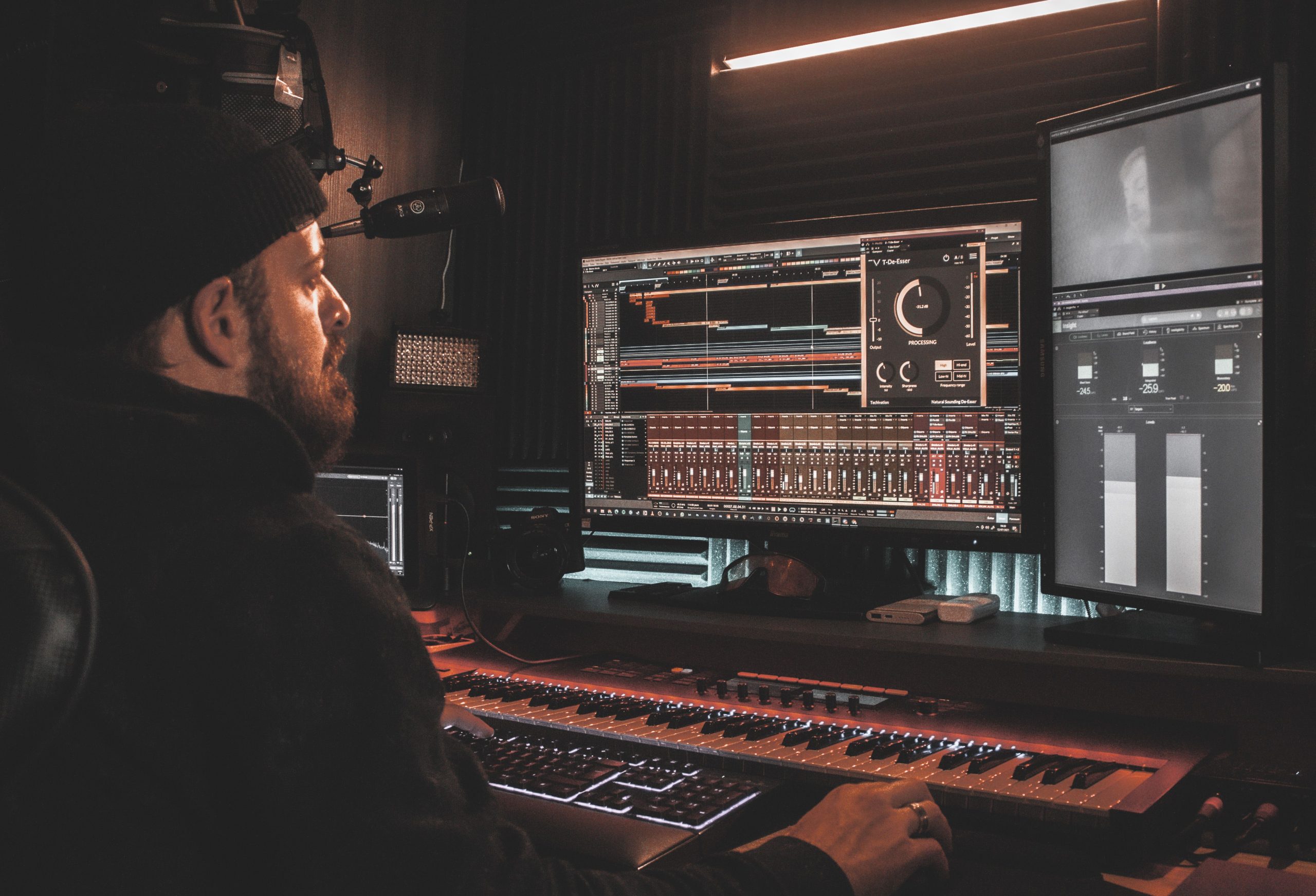 Ljudtekniker vid två skärmar med flerspårssession och ett öppet processningsplugin i en hemmastudio