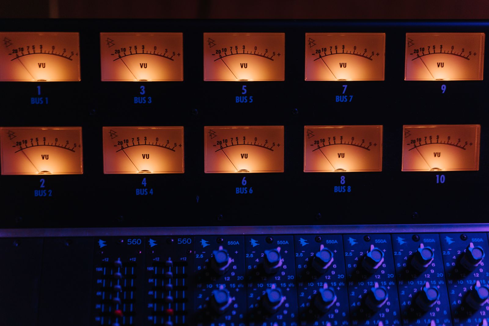 Rad av upplysta VU-mätare på ett mixerbord i en studio