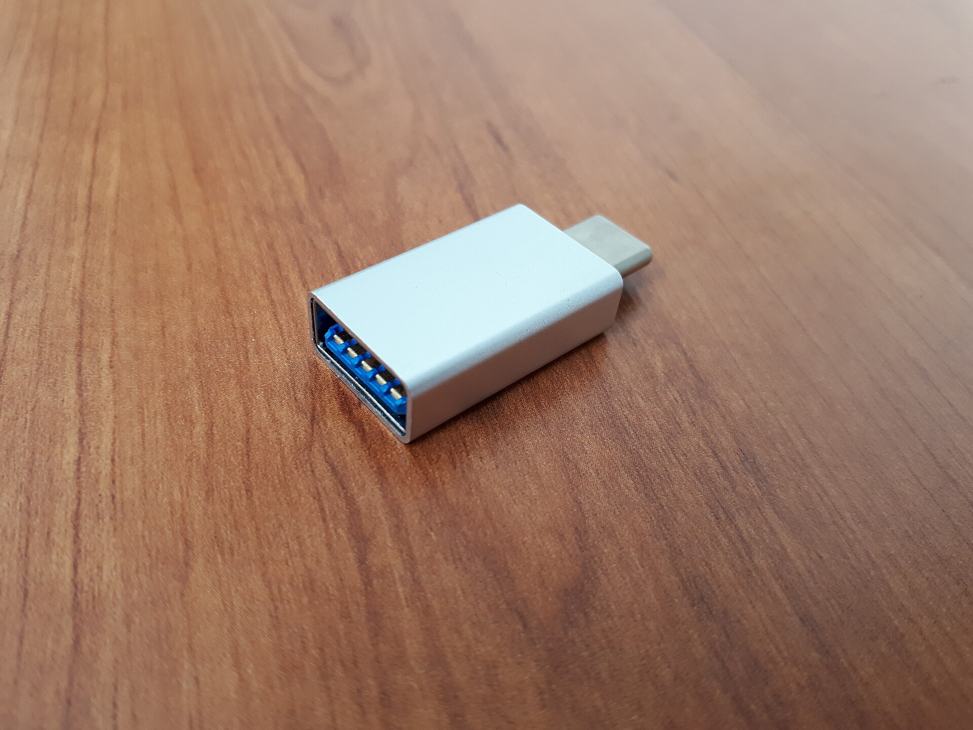 Adapter med USB-C-kontakt i ena änden och ett USB-A-uttag i den andra, liggande på ett träbord