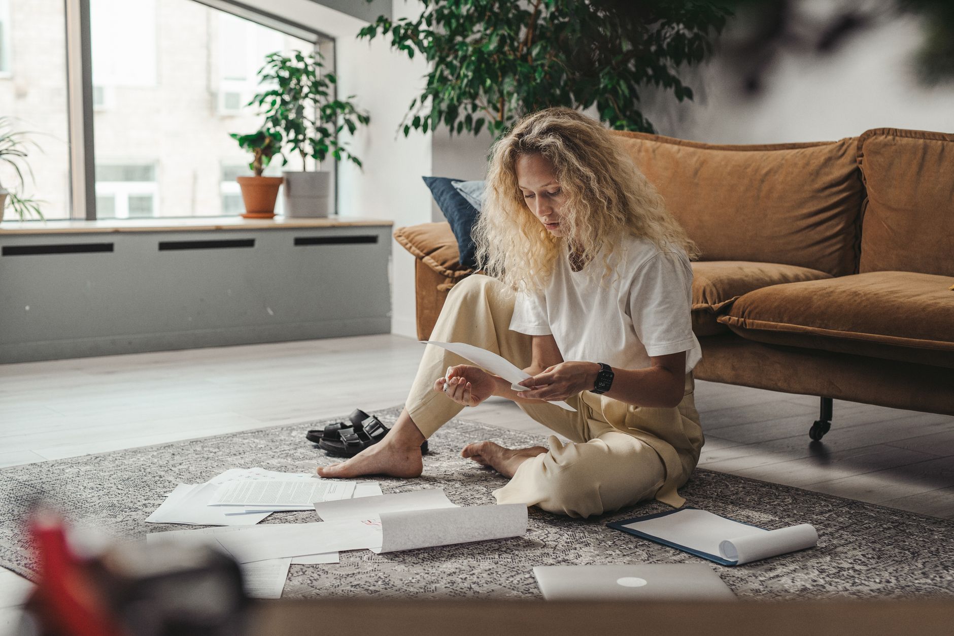 Ung kvinna sitter på golvet och läser ett brev bland papper och dokument