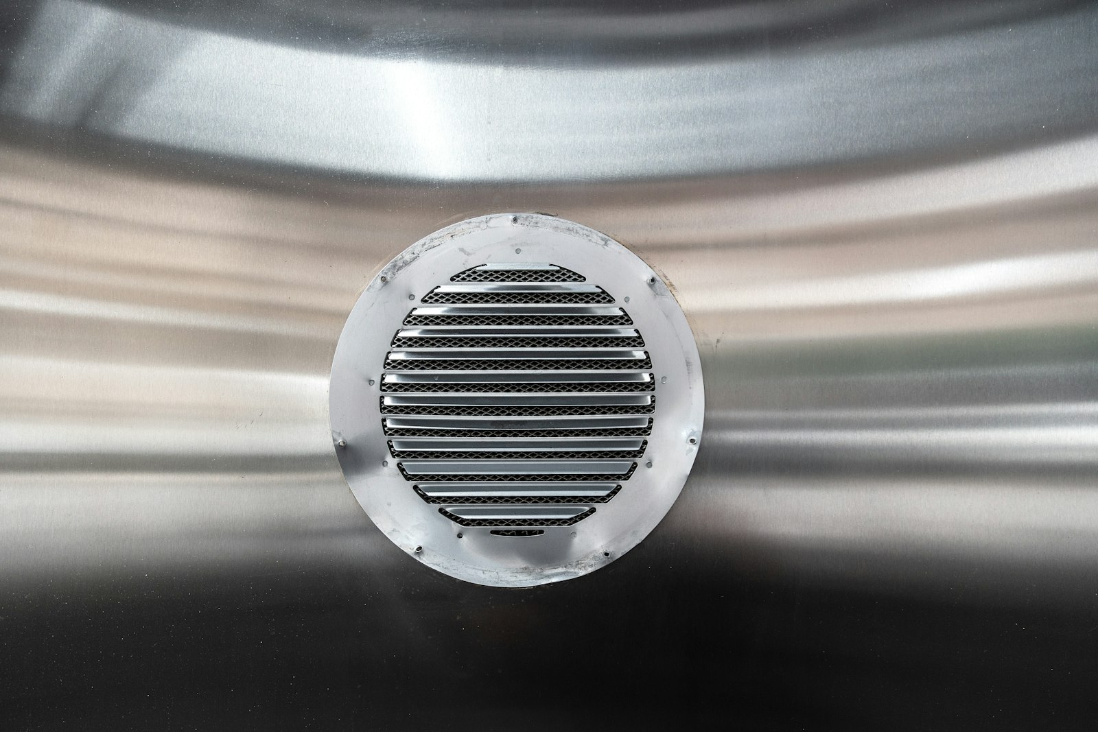 Runt ventilationsgaller av aluminium monterat i en metallvägg