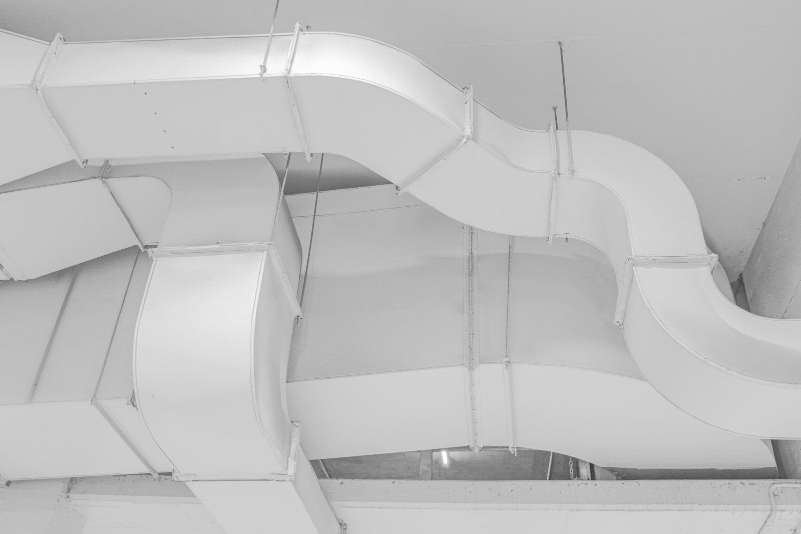 Vita ventilationskanaler i plåt monterade under ett betongtak