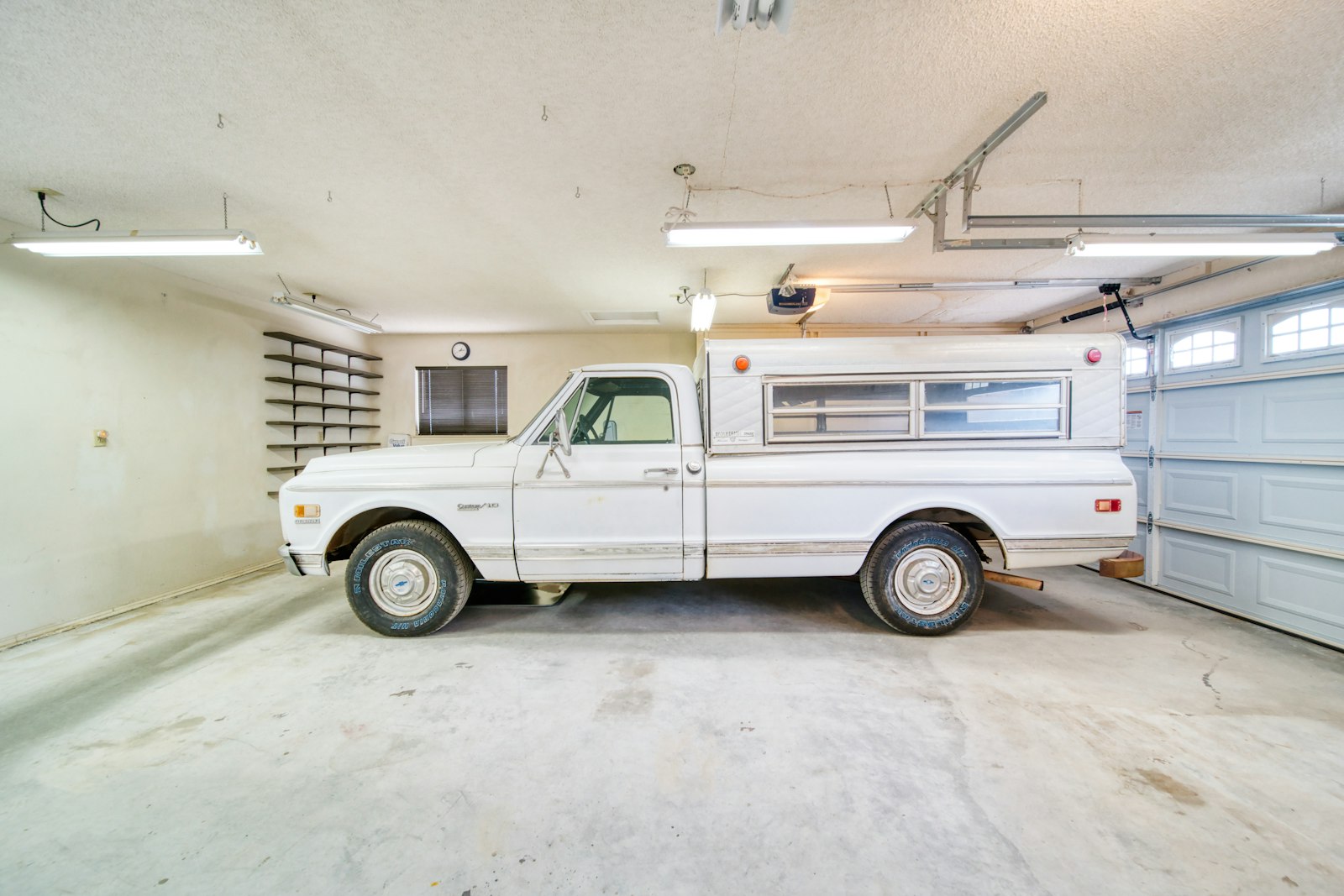 Vit pickup parkerad i ett ljust villagarage med garageport