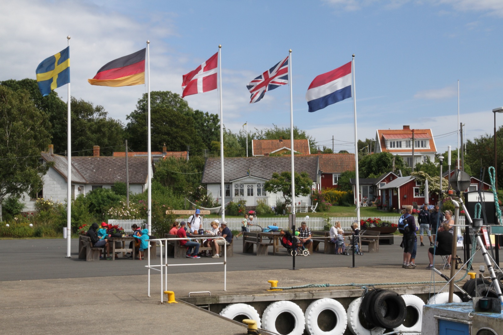 Folkliv vid Hanö hamn med flaggor och bänkar en sommardag