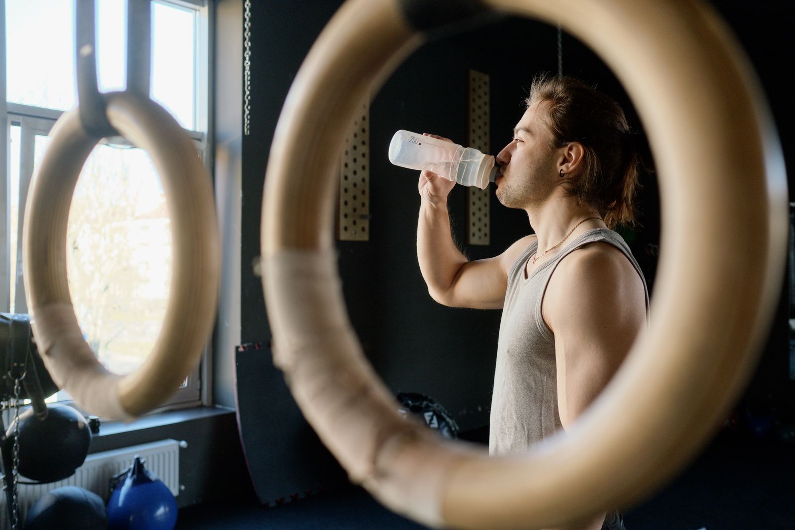 Person dricker vatten ur en sportflaska i ett gym