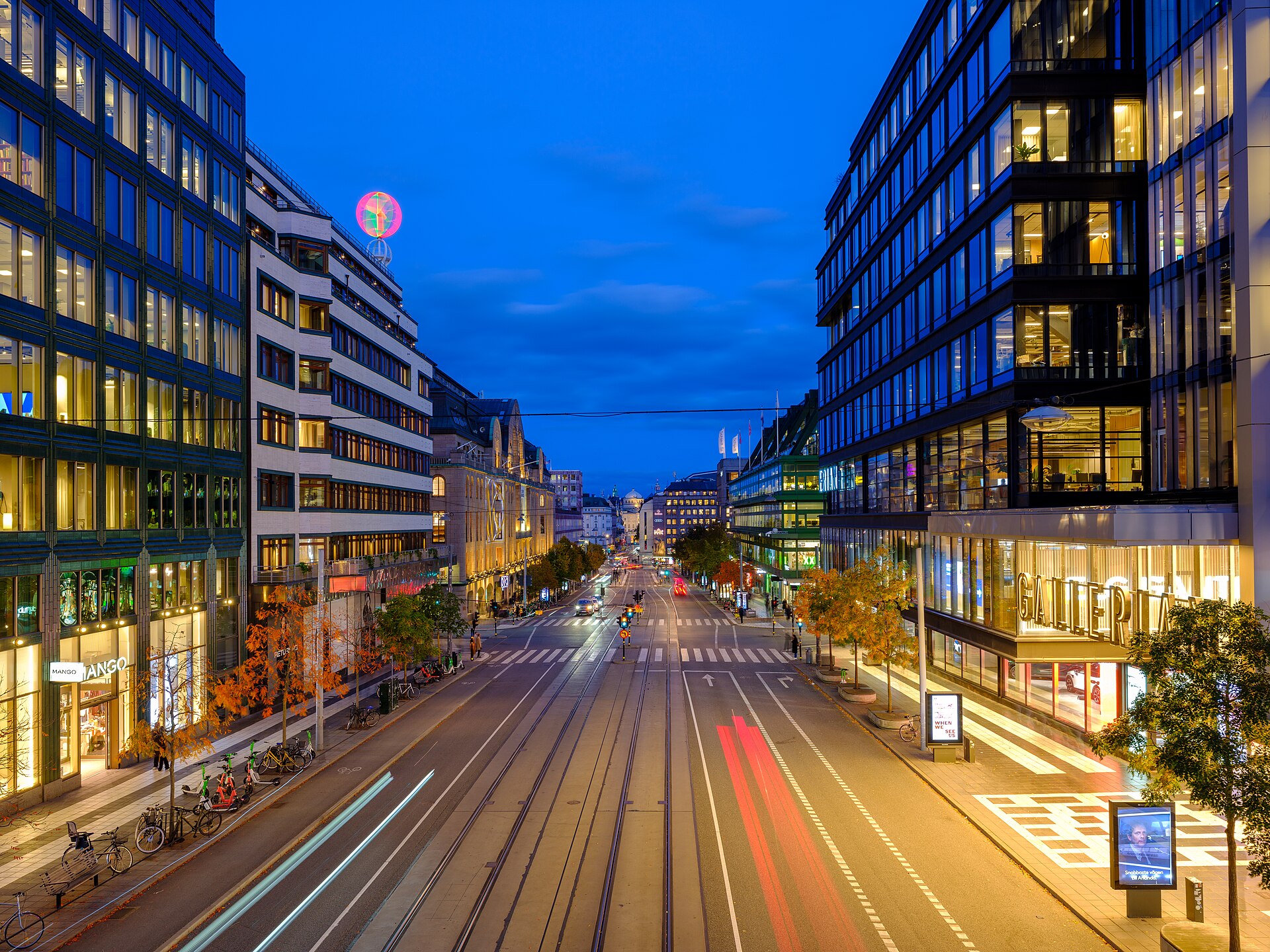 Hamngatan i Stockholm en höstkväll, med Gallerians fasad till höger och butiker och varuhus längs gatan.