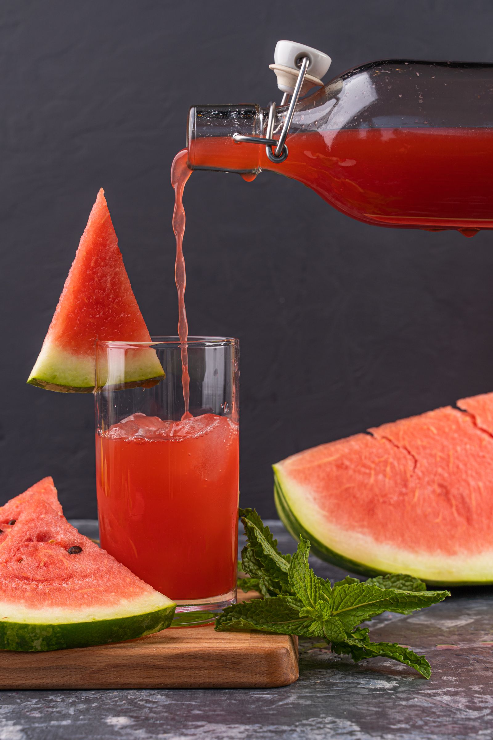 Röd bärsaft hälls från en glasflaska med patentkork ner i ett glas