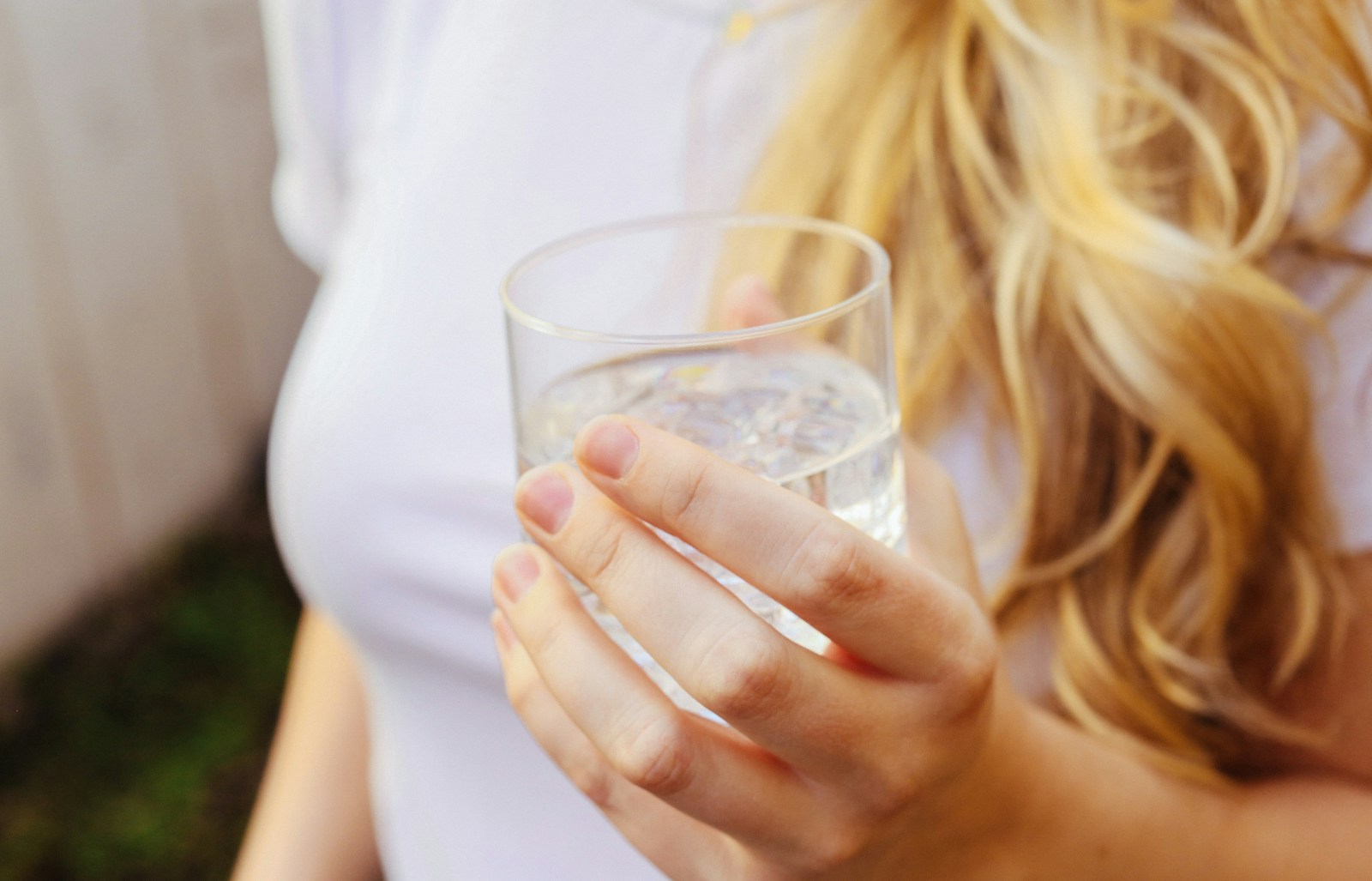 Person som håller ett glas vatten, ökad törst är ett vanligt tecken på högt blodsocker