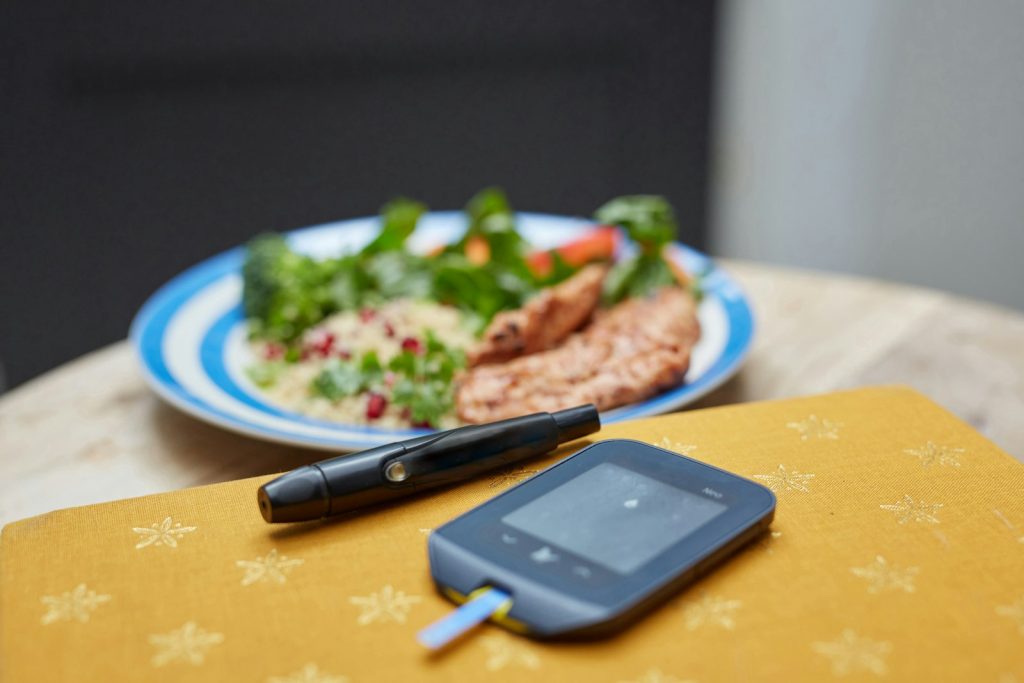 Blodsockermätare och fingerstickspenna framför en middagstallrik.