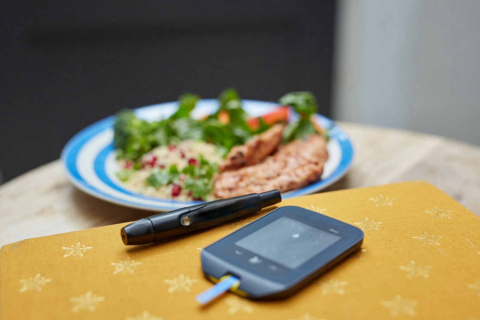 Blodsockermätare och fingerstickspenna framför en middagstallrik.