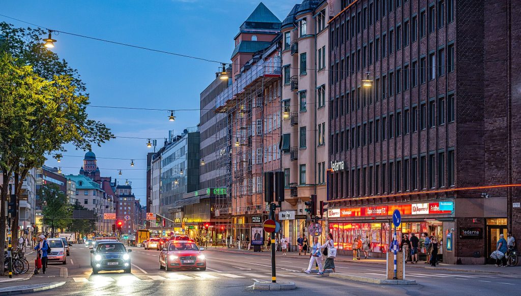 Sankt Eriksgatan på Kungsholmen en sommarkväll, med bilar, fotgängare och upplysta butiker i gatuplan
