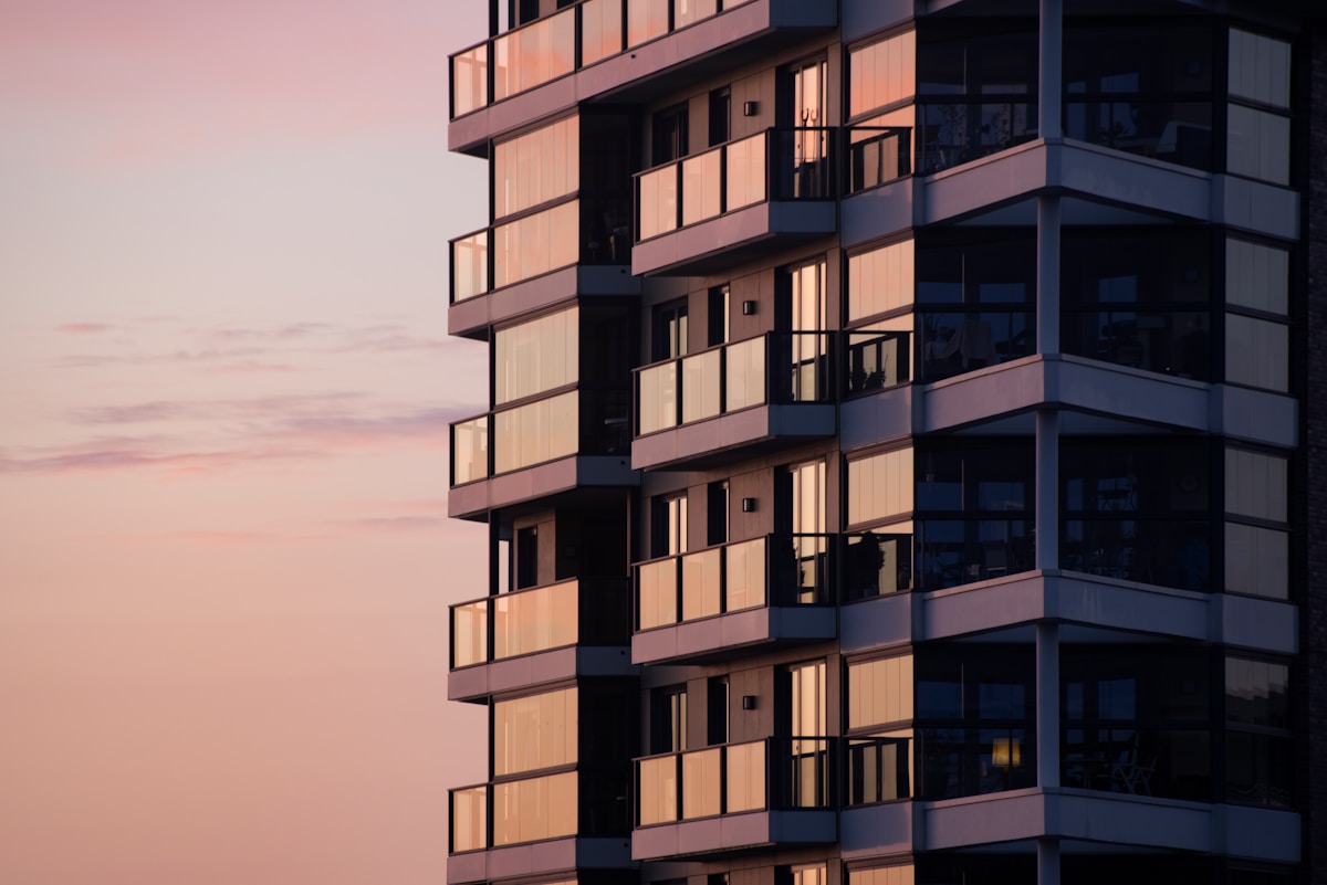 Flerbostadshus i skymning med balkonger och upplysta lägenheter