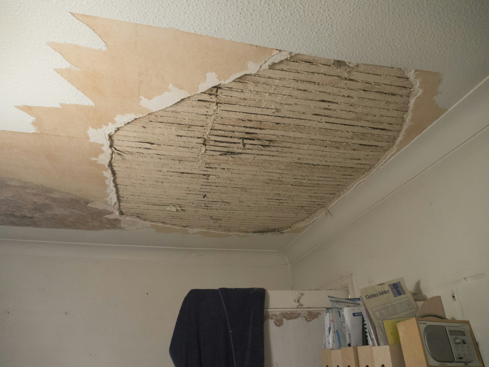 Innertak i ett bostadsrum där putsen lossnat och blottat träreglar efter en vattenskada