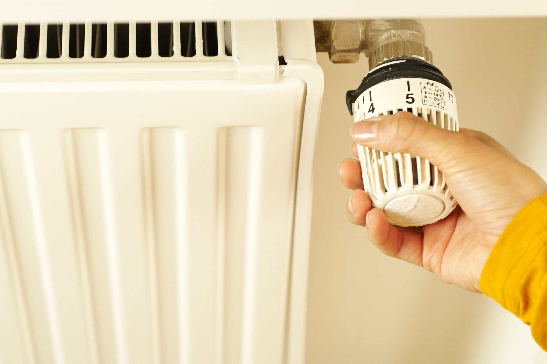 Hand som vrider på termostaten till ett element