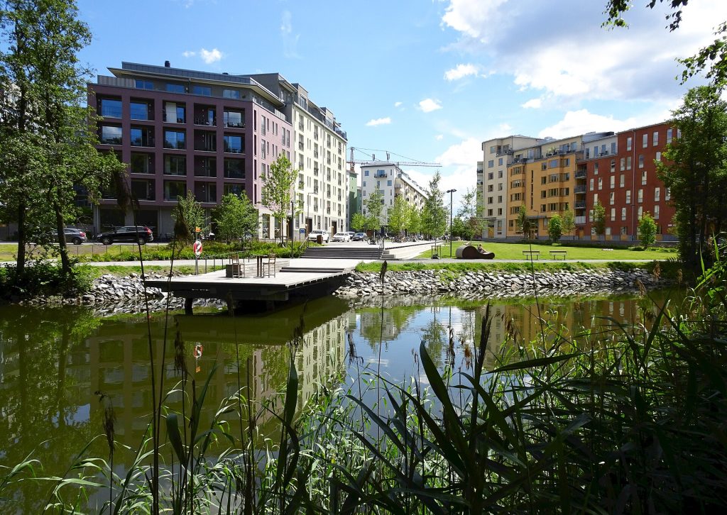 Nybyggda flerbostadshus i olika färger vid Husarviken i Norra Djurgårdsstaden i Stockholm, med en byggkran i bakgrunden