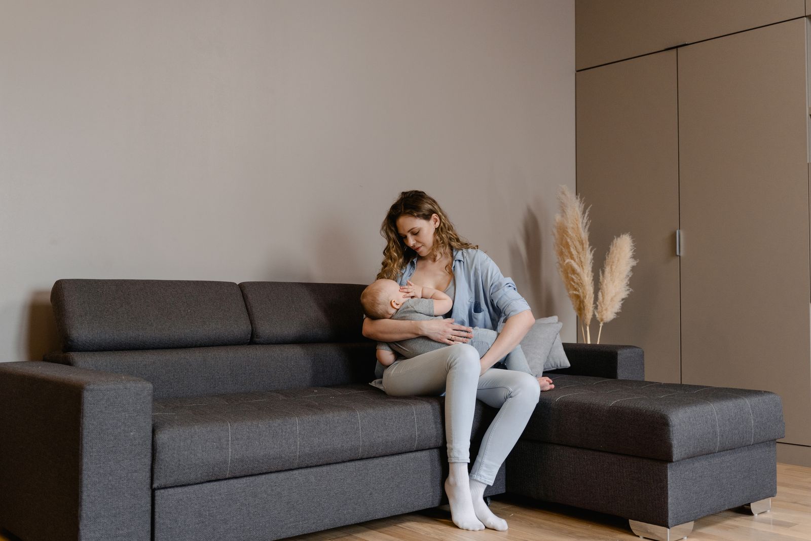 En förälder ammar sitt barn sittande i en soffa