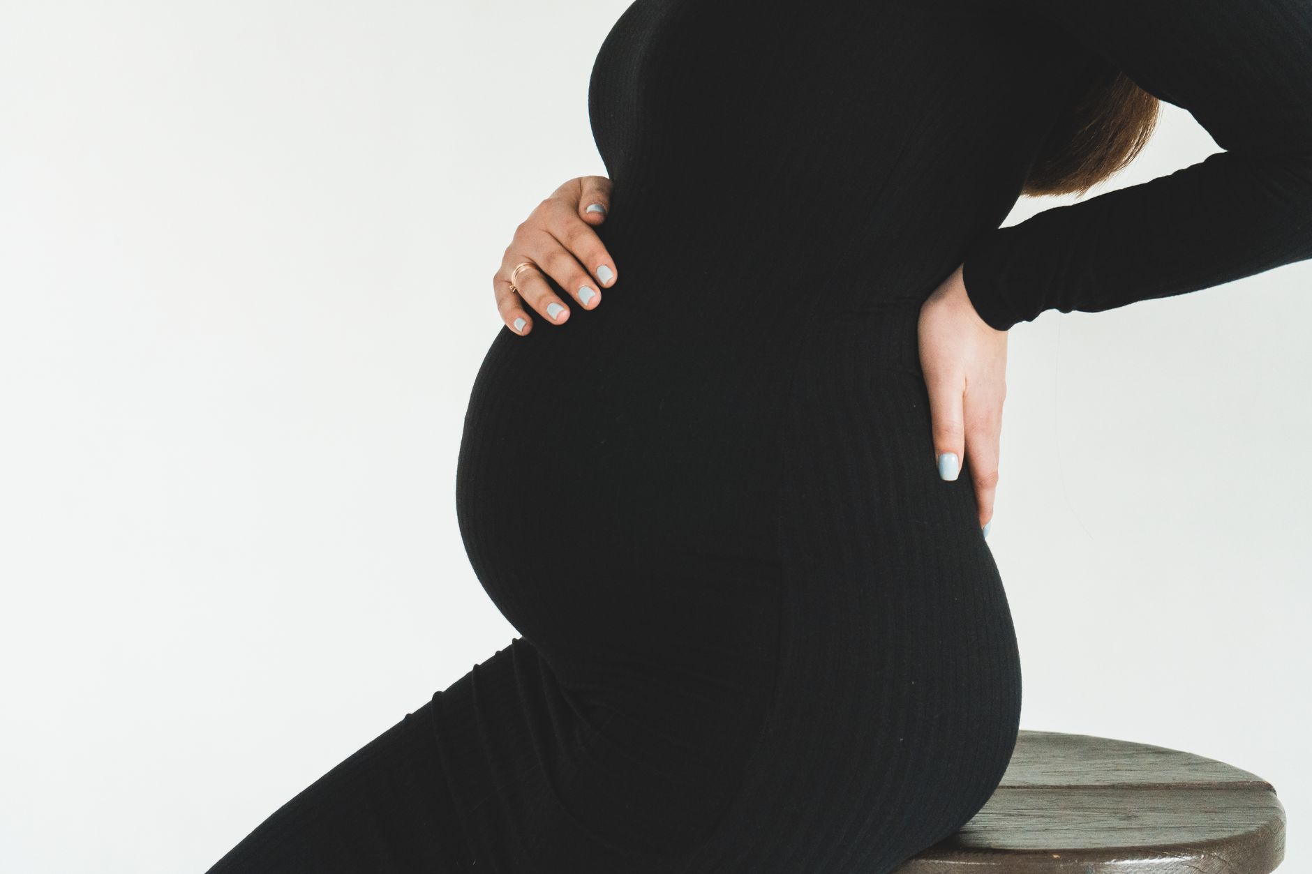 Gravid kvinna med ena handen på magen och den andra på ländryggen