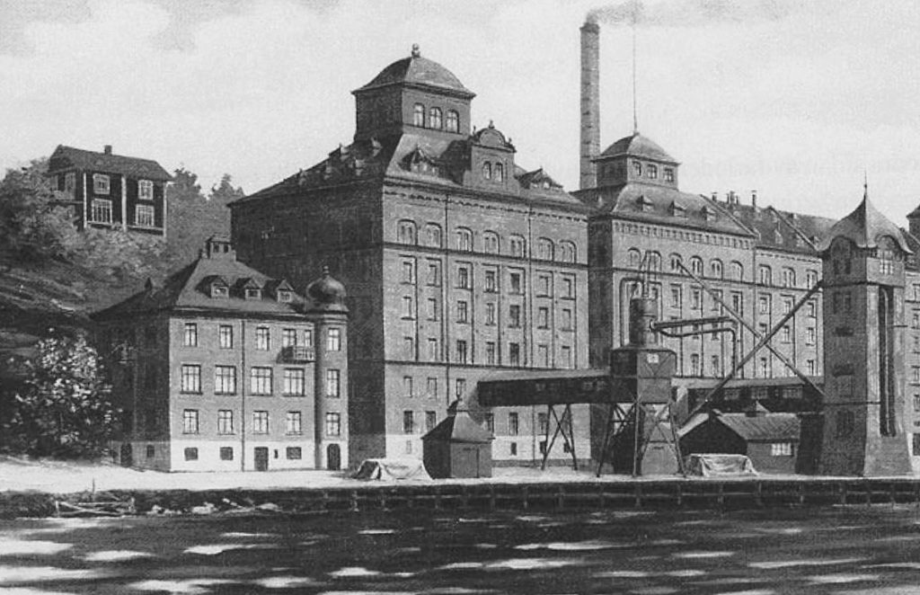 Kvarnen Tre Kronor på Kvarnholmen i Nacka fotograferad från vattnet 1925, med kontorsbyggnaden till vänster och Silo III till höger