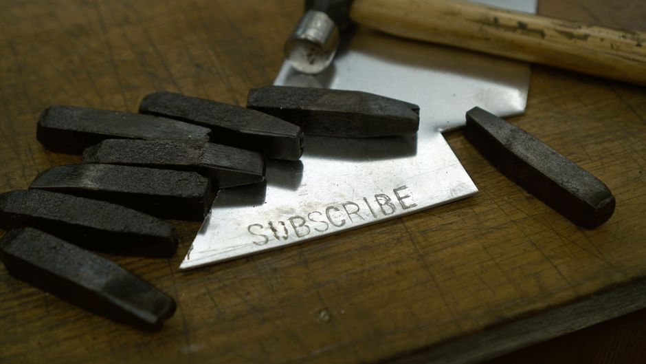 Bokstavsstämplar och en hammare bredvid en metallplatta med instansad text