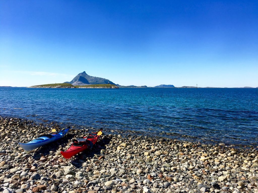 Två havskajaker uppdragna på en stenstrand vid en klippig kust